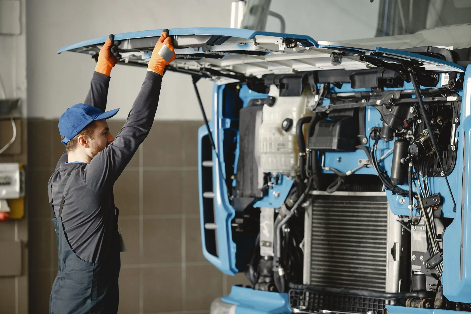 A fleet mechanic inspecting the exposed front of a truck